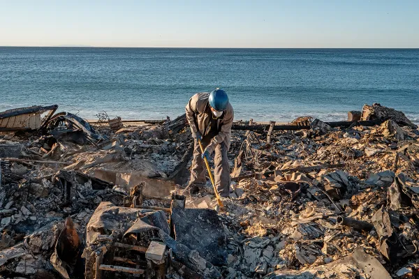 A first responder cleans up debris from the LA fires.