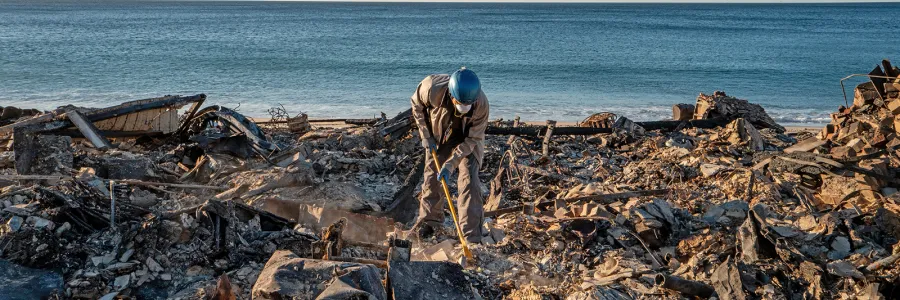 A first responder cleans up debris from the LA fires.