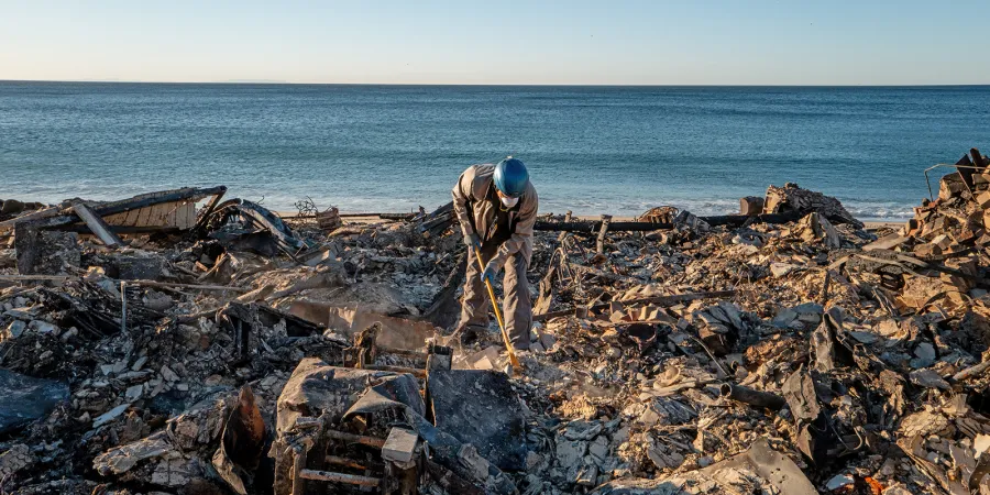 A first responder cleans up debris from the LA fires.