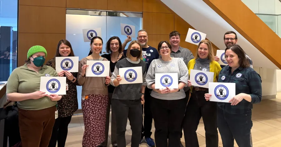 American Library Association employees hold up signs with their new union logo on them.