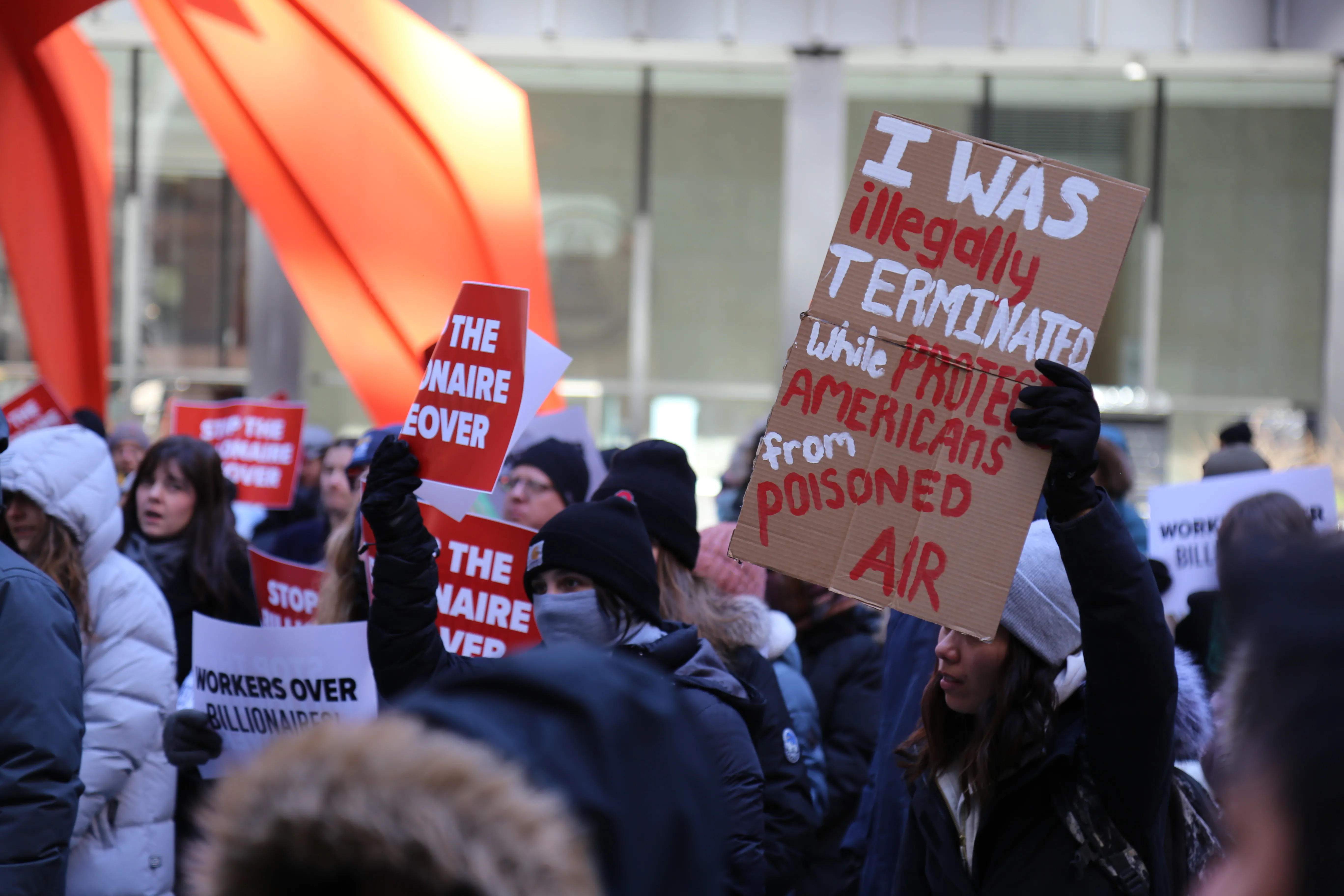 AFGE member holding sign saying "I was illegally terminated while protecting Americans from poisoned air" 